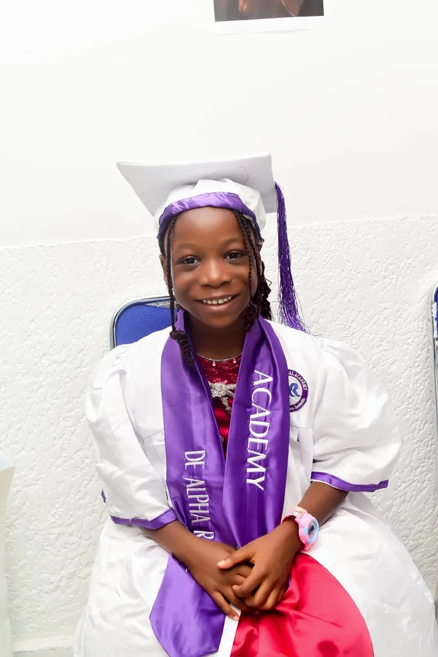 A young graduate in cap and gown smiling on graduation day