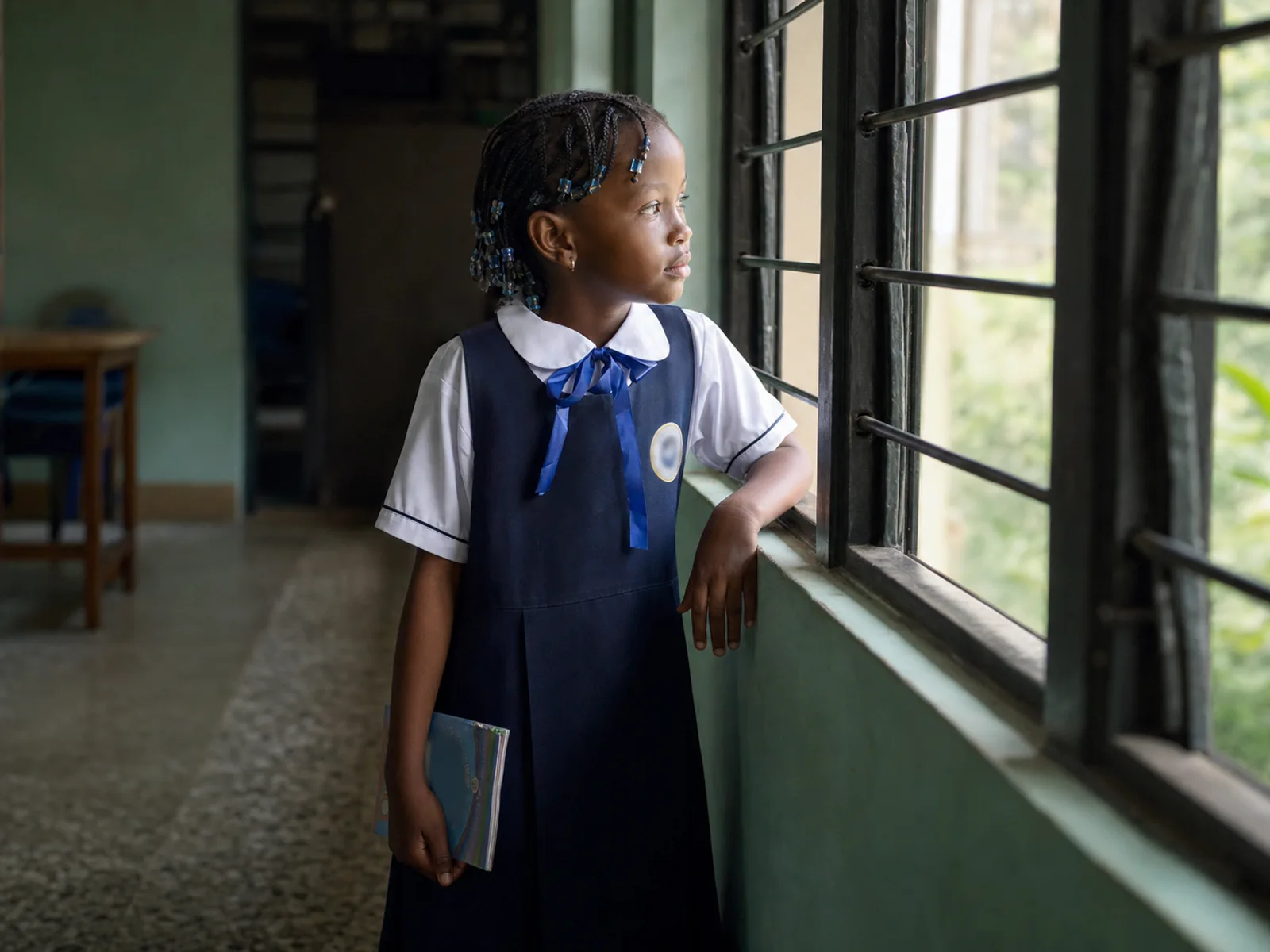 A child looking thoughtfully through a classroom window