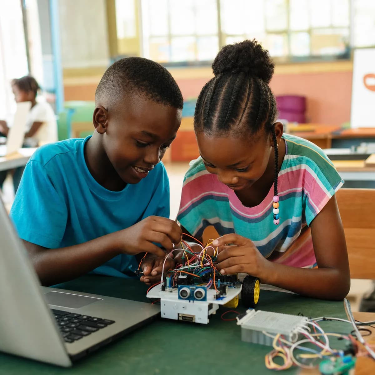Two children building a small wheeled robot