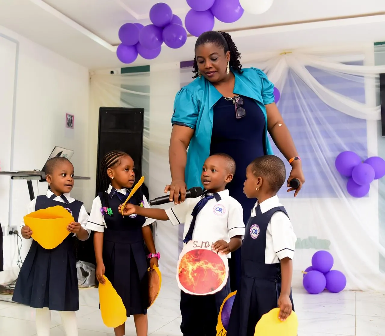 A teacher and young pupils presenting their craft work together